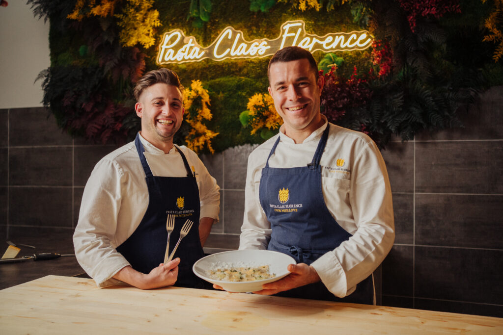 two people in front of camera making pasta class