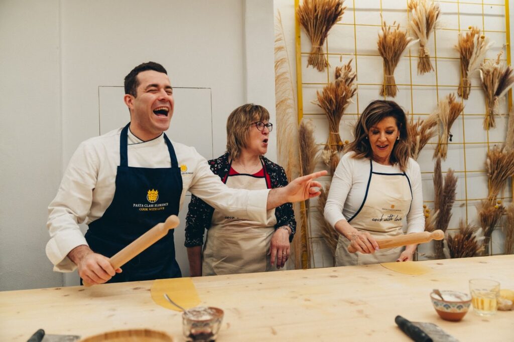 chef and two partecipants laughing during a pasta class