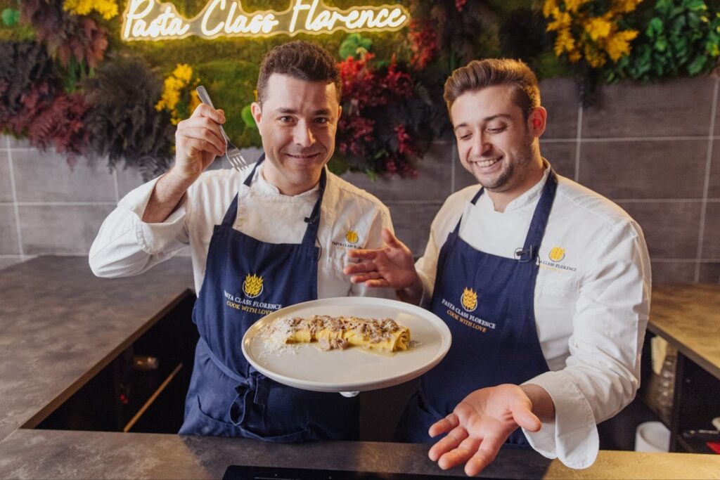 two chef cooking a plate of pasta with lamb ragù