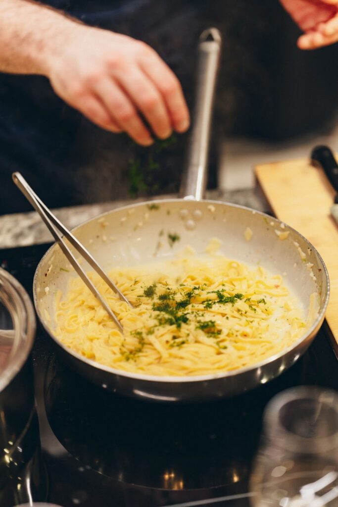 a pan cooking fresh pasta with herbs