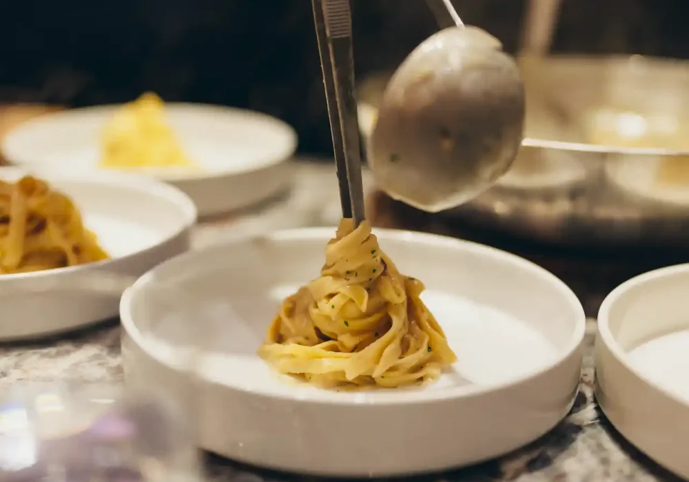 chef serving pasta in a plate