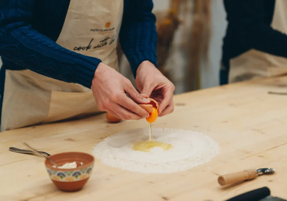person breaking an egg on the flour